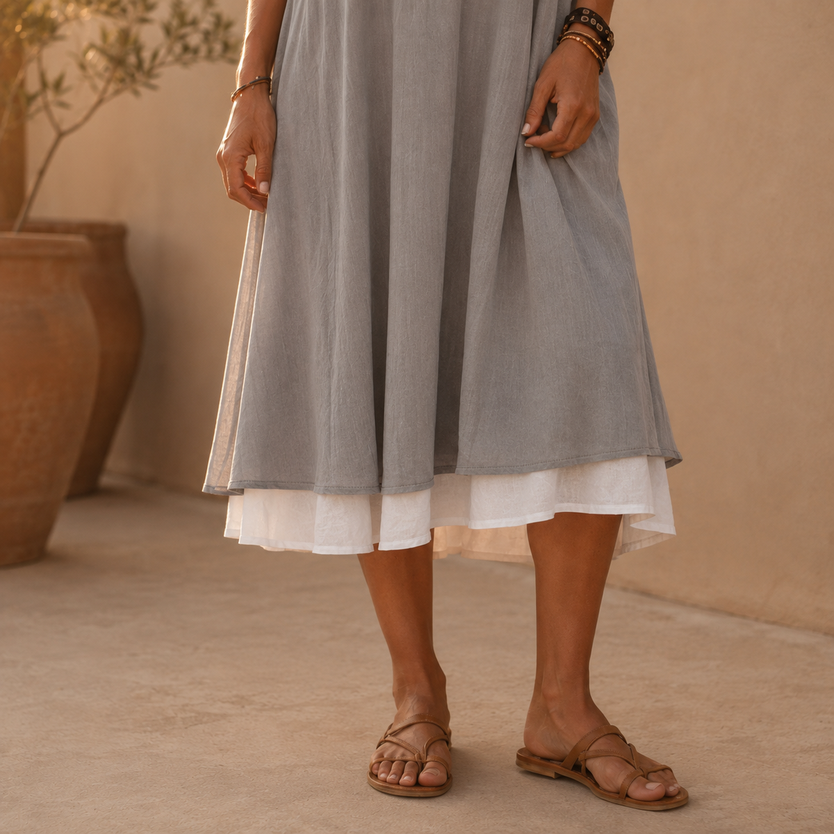 Vestido gris con dobladillo y capa interior blanca, con sandalias marrones