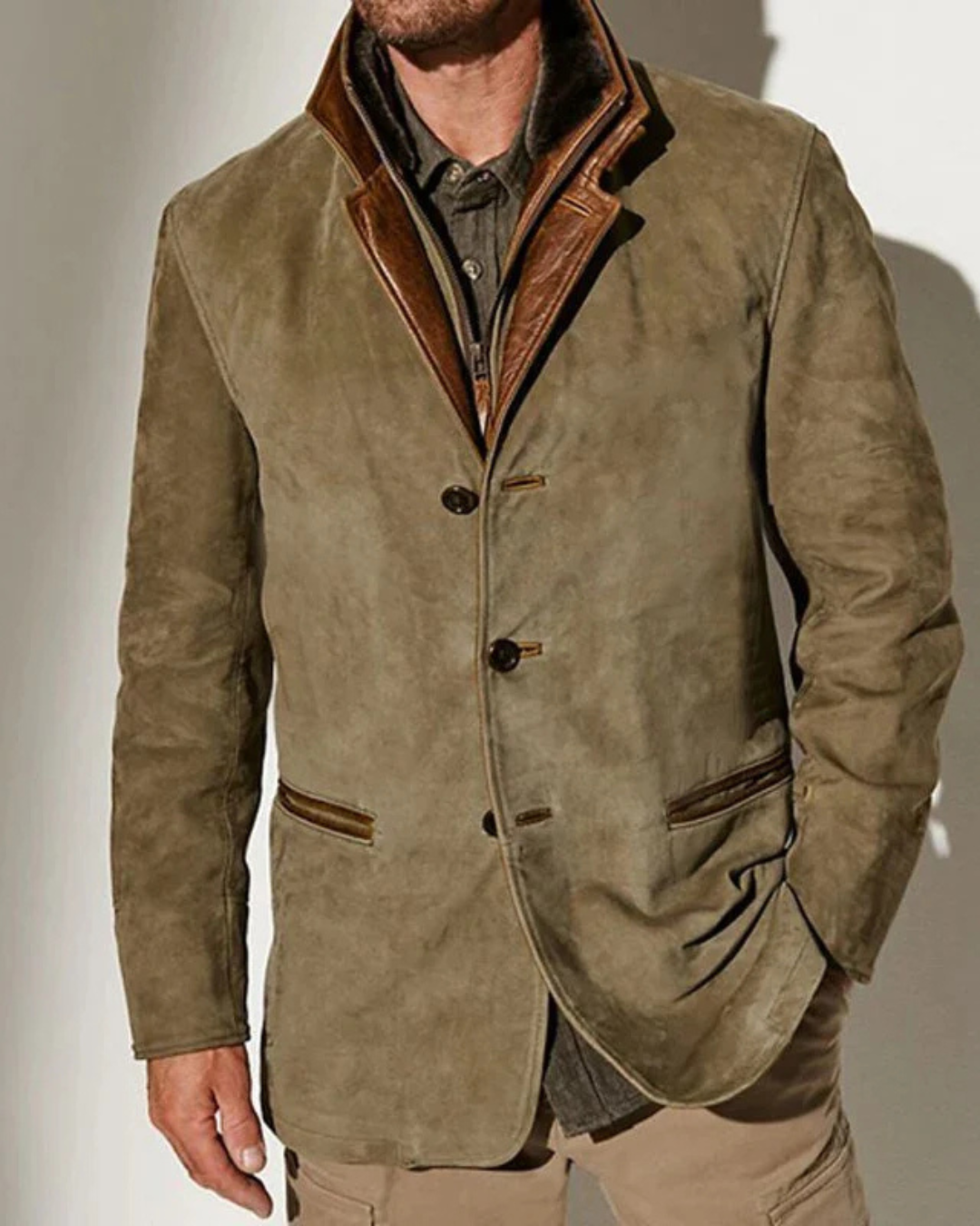 Chaqueta de ante verde oliva con solapa y ribete marrón, bolsillos y costuras decorativas.