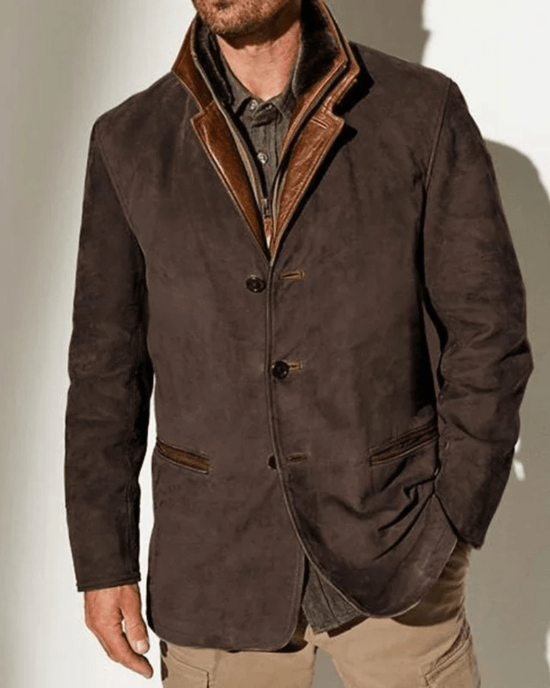 Chaqueta de ante marrón oscuro con solapa y ribete marrón, botones y bolsillos laterales.