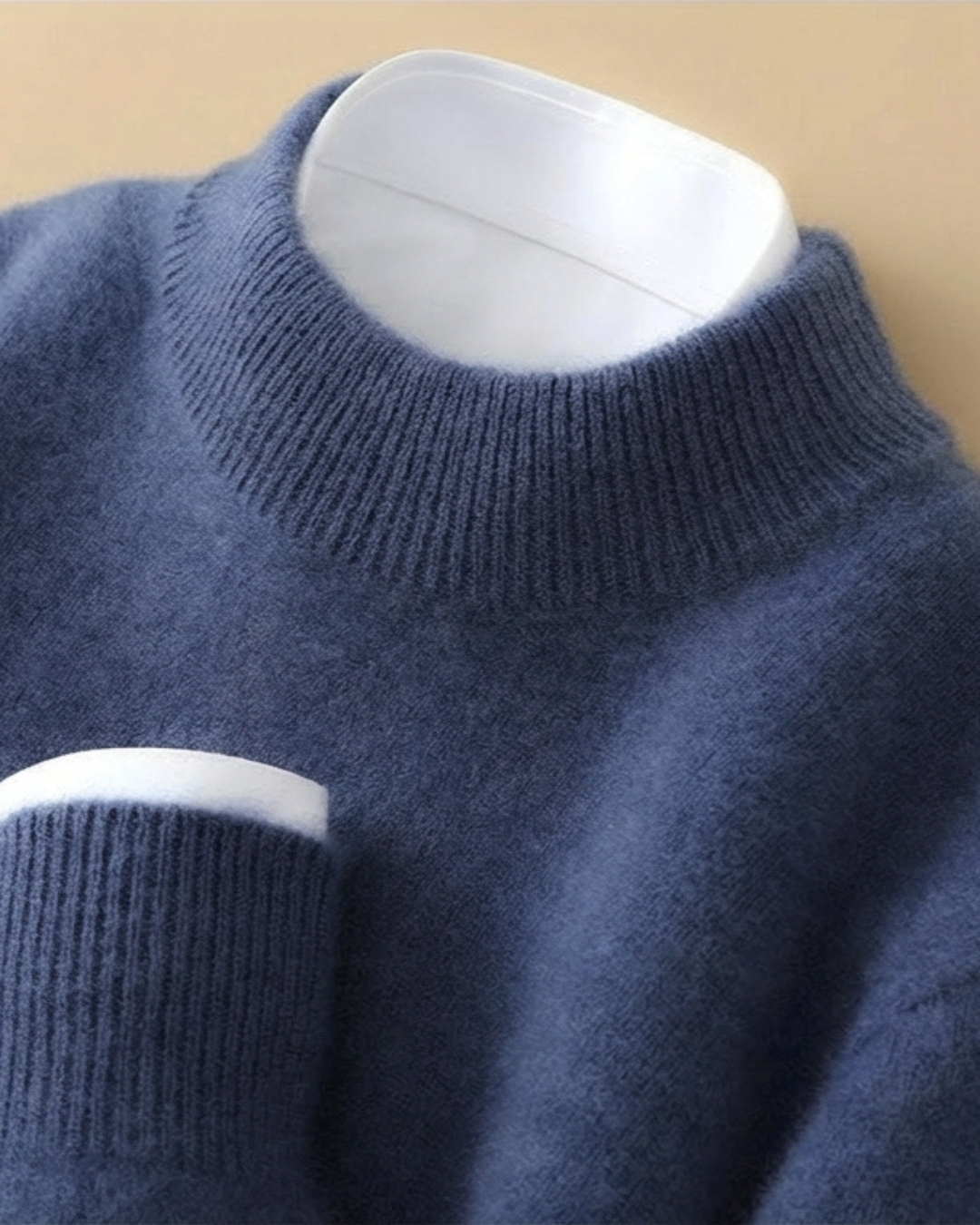 Jersey de punto azul con cuello alto de canalé y puños y bastilla en blanco.